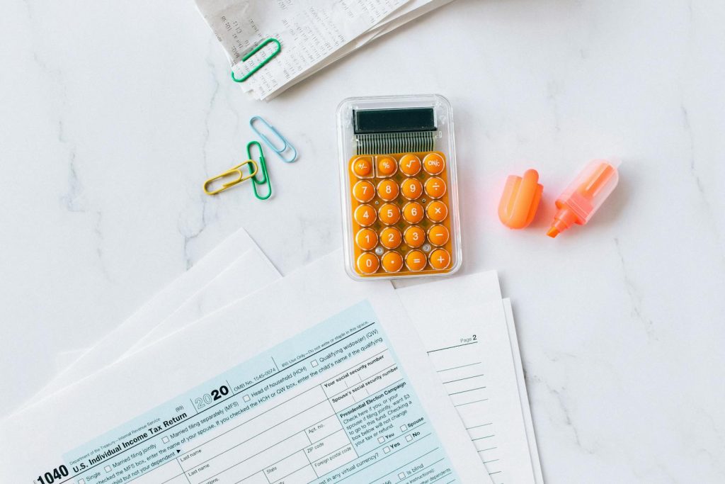 A flat lay image of tax forms, calculator, and office supplies on a desk.